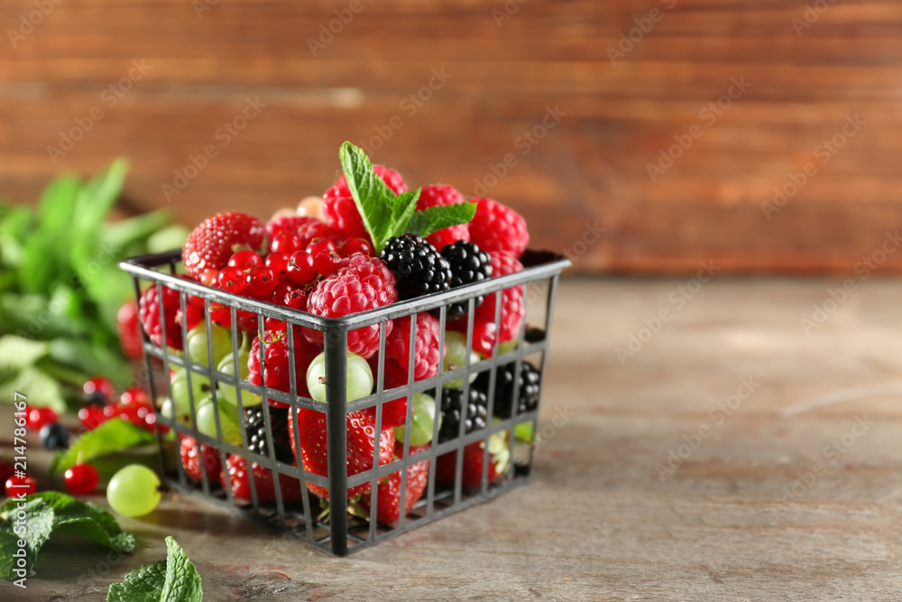 Basket with delicious berries on wooden background