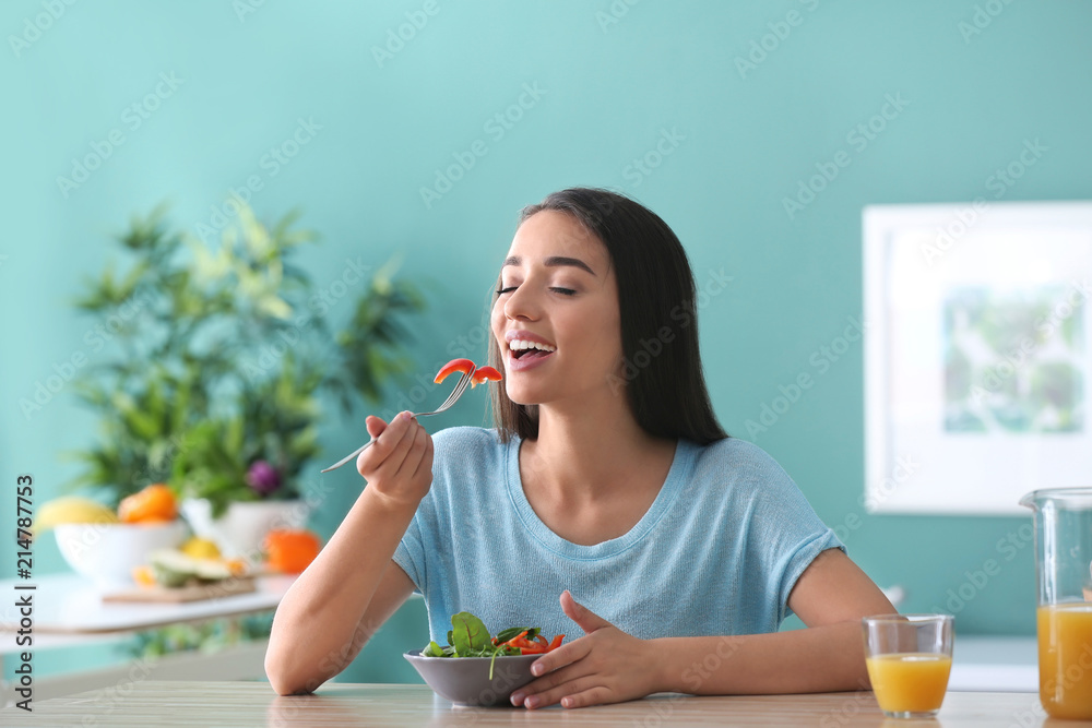 年轻女子在厨房吃健康沙拉配蔬菜