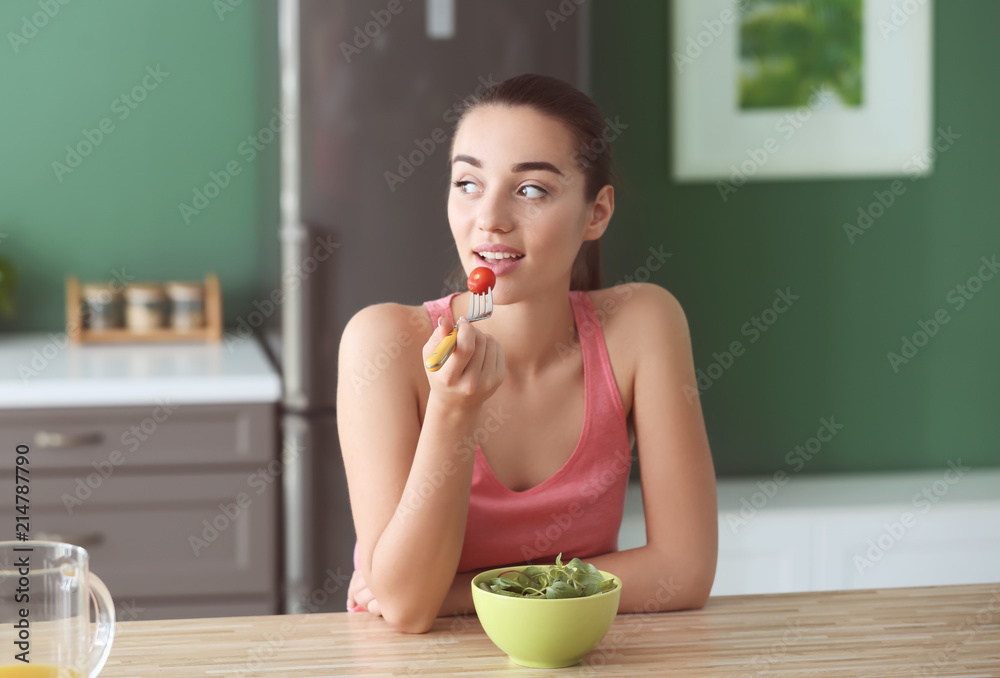 年轻女性在厨房里吃蔬菜沙拉