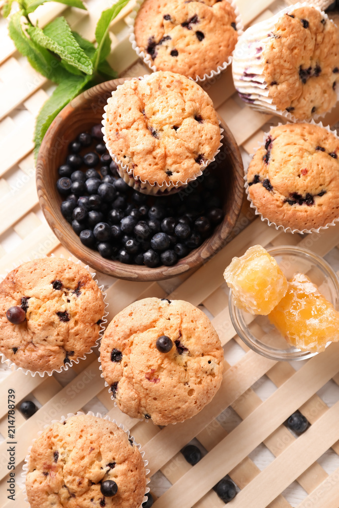 Tasty blueberry muffins with fresh berries and honey on table