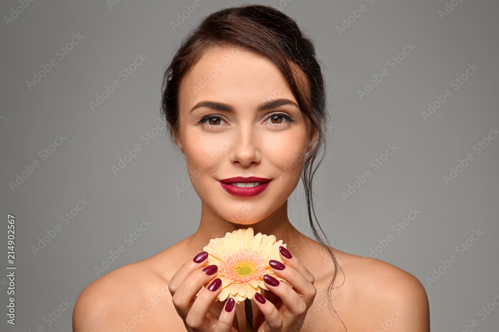 漂亮的年轻女人，专业美甲和灰色背景的花朵