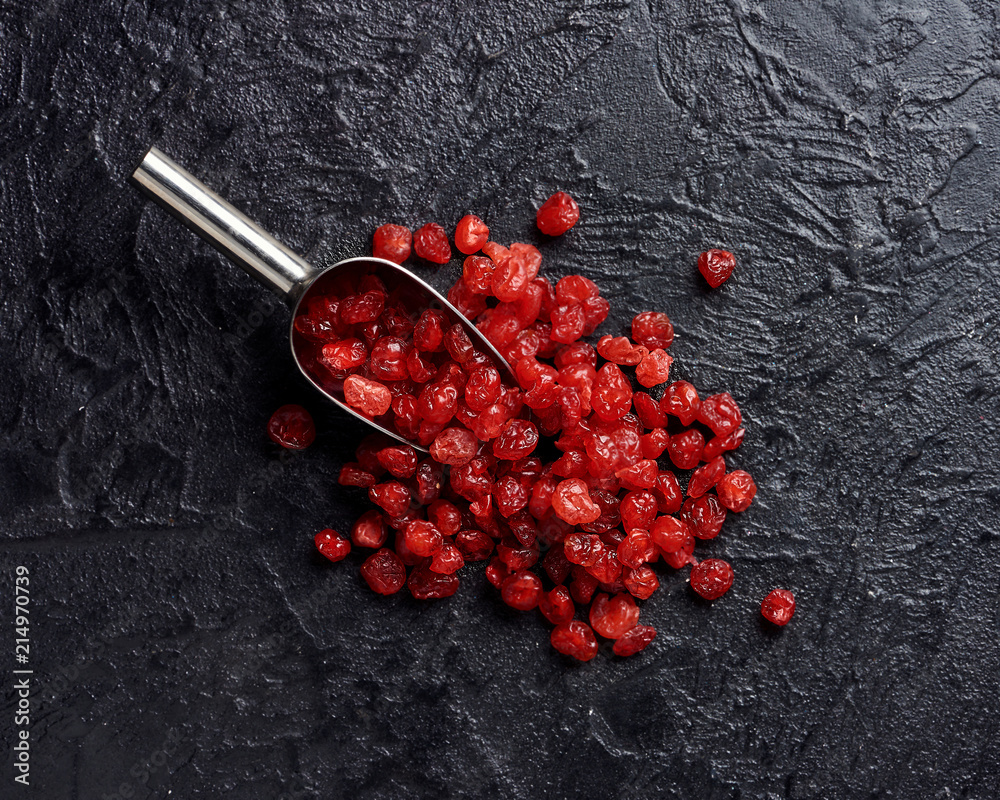 Dried red cherry on black background with scoop