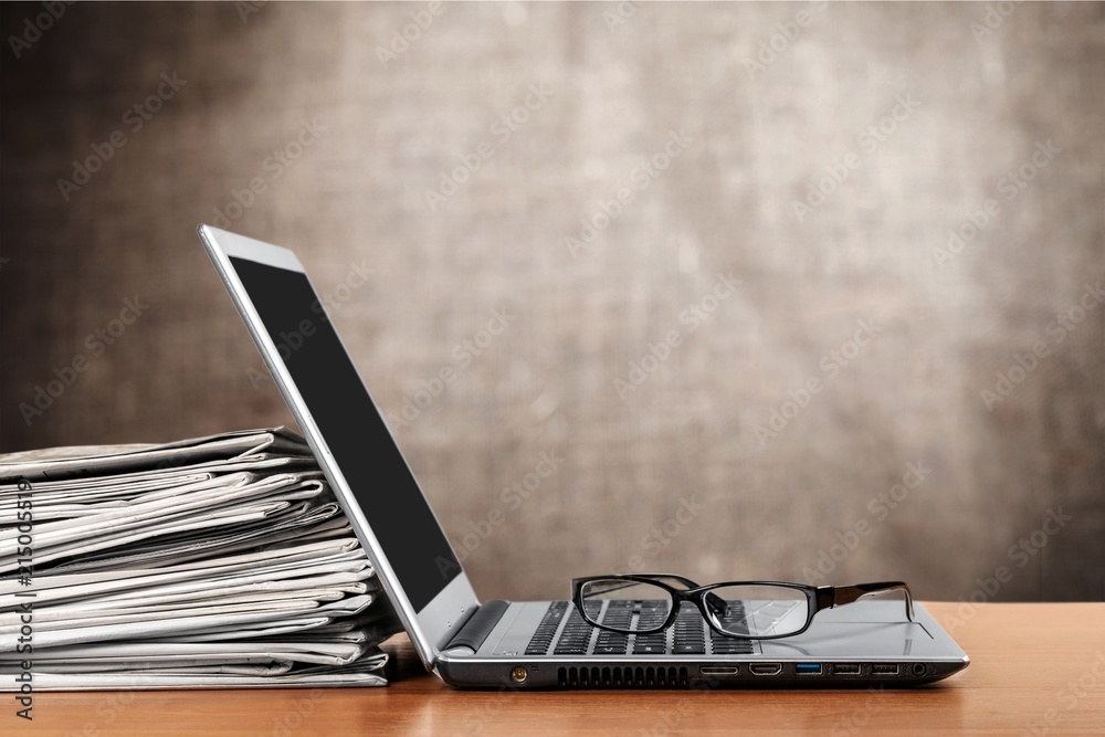 Laptop and black glasses on background