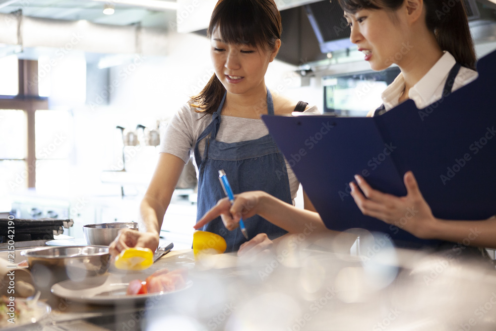 料理教室で野菜を切る生徒とそれを見守る講師