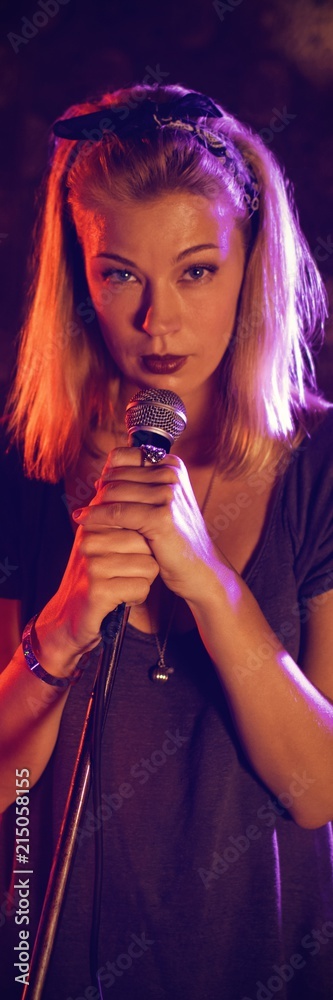 Confident female singer with drummer performing on illuminated