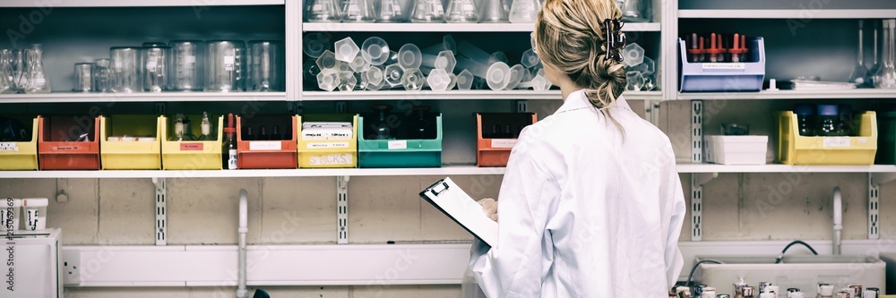 Serious female scientist writing on her clipboard