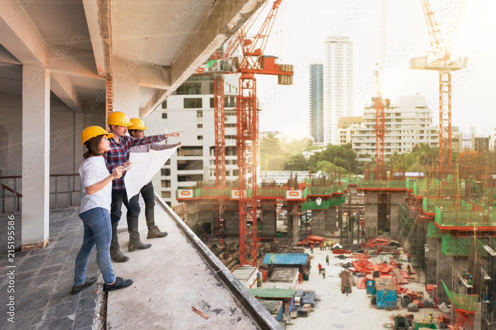 3名建筑工程师在施工现场共同讨论蓝图