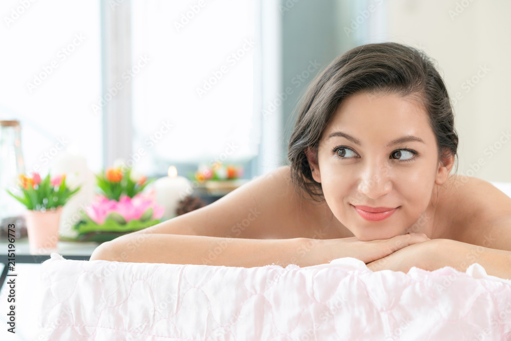 Relaxed young woman lying on spa bed for massage.