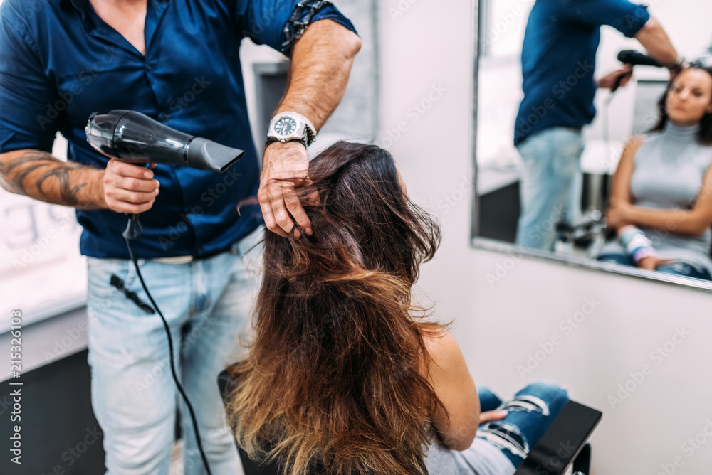 Hairdresser dries hair with a hairdryer in a salon.