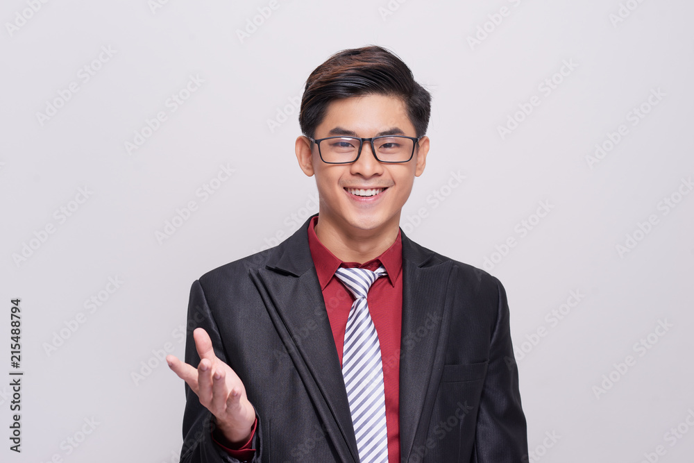 Handsome and well dressed businessman in a suit, tie and vest, standing against a white background s