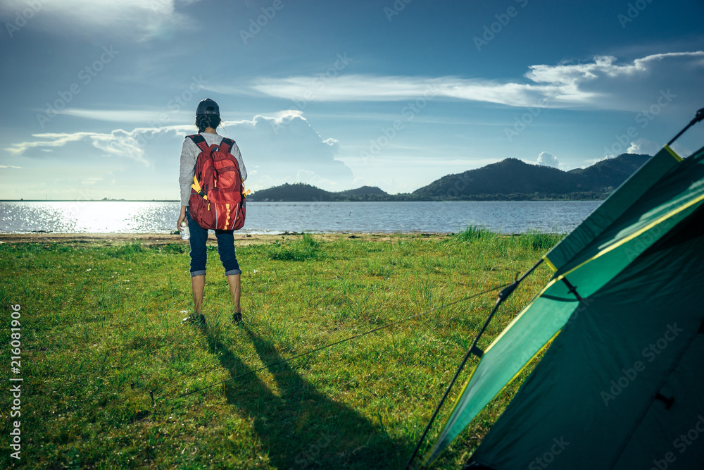 Asian young woman is camping and walking along the road into the forest on weekend, Travel relaxing 