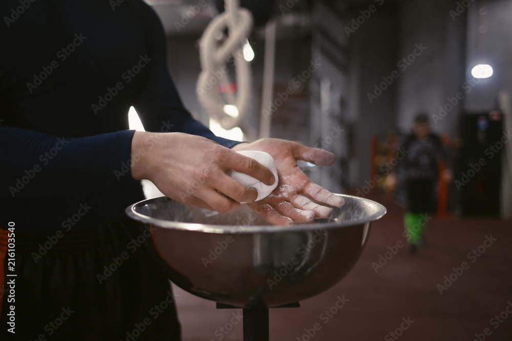 Sportsman applying magnesia on hands in gym, closeup