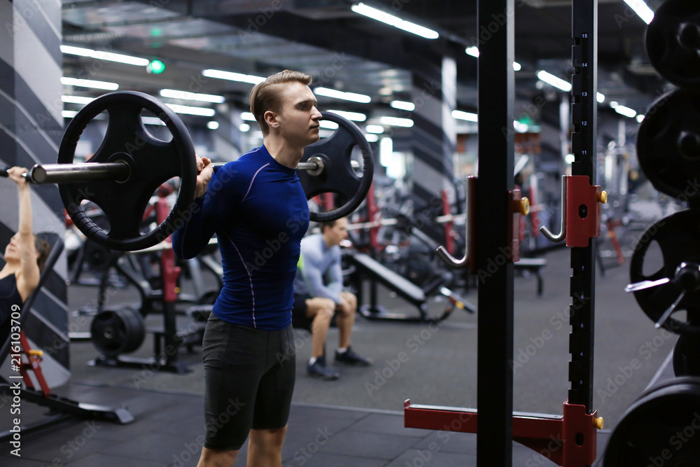 Athletic man training with barbell in modern gym