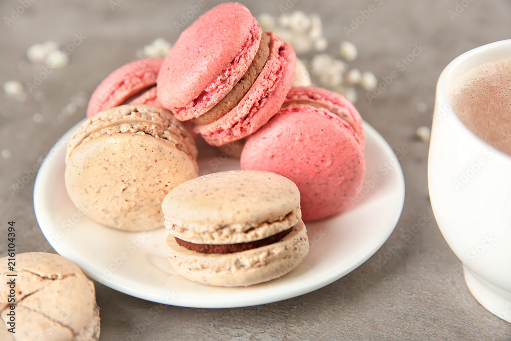 Plate with tasty macarons on table