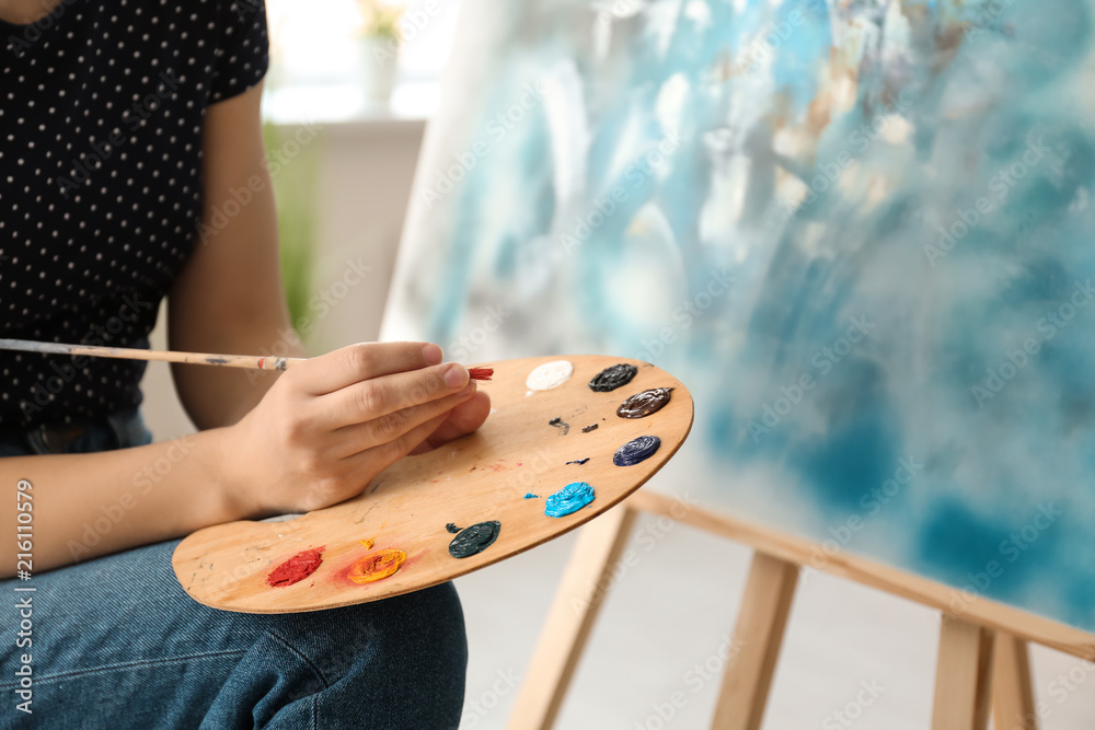 Female artist painting picture in workshop, closeup