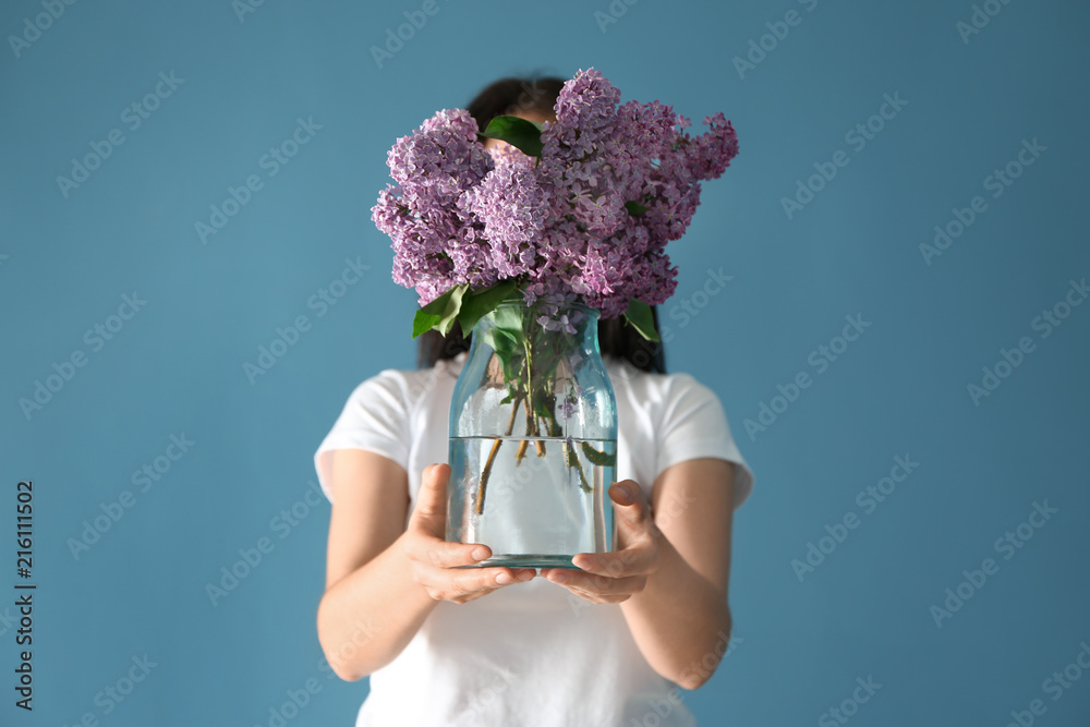 女人拿着花瓶，背景是美丽的淡紫色花朵