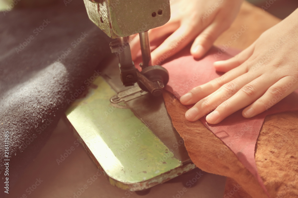 Woman using sewing machine in leather workshop