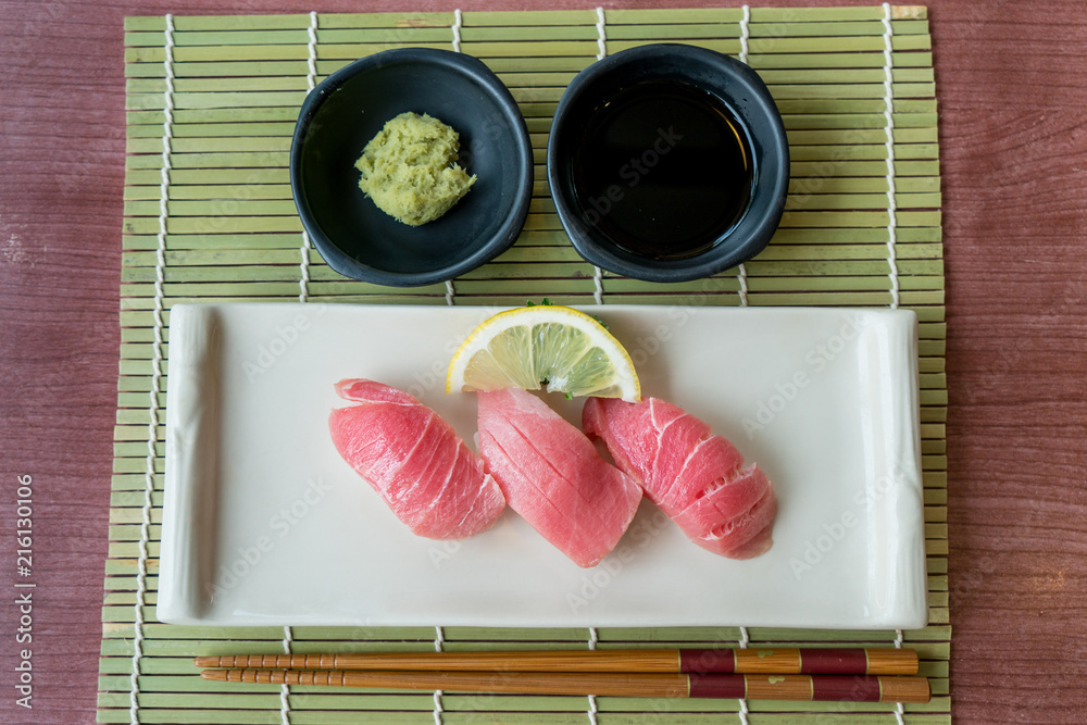 Otoro tuna sushi on black plate along with Japanese sauce and green leaf decoration, Japanese food, 