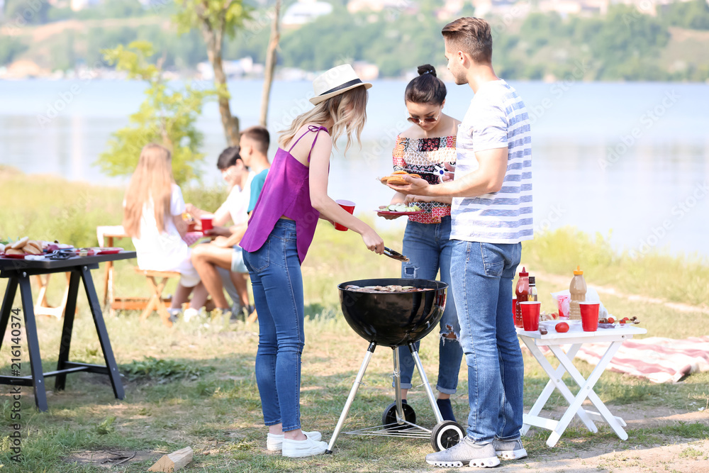 Young people having barbecue party on sunny day outdoors