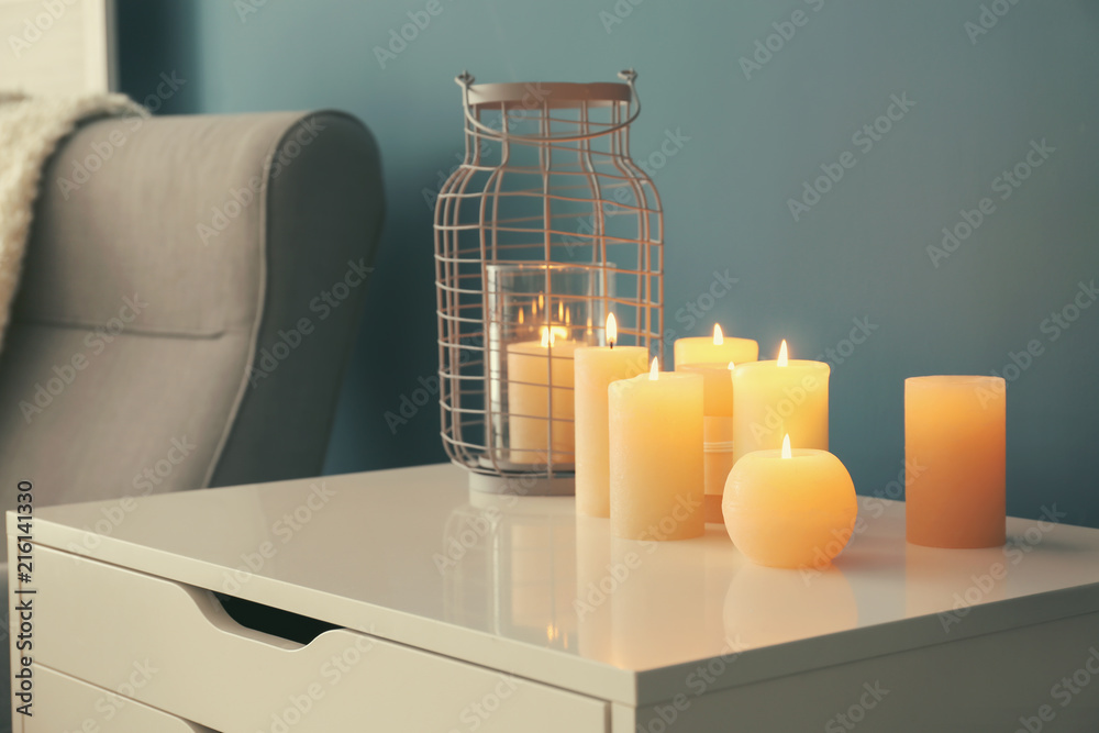 Commode with burning wax candles in living room