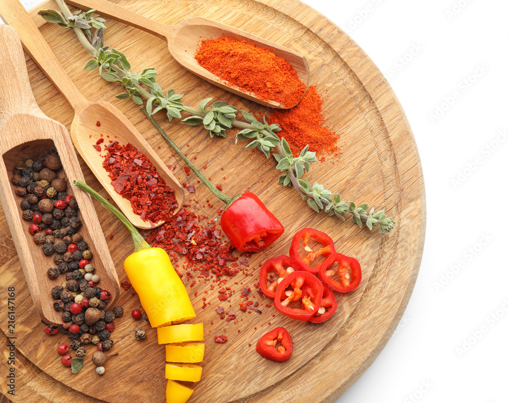 Wooden board with chili pepper, herbs and spices on white background