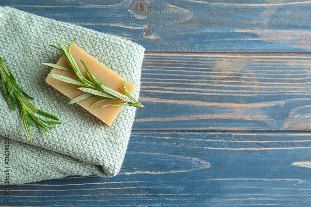 Handmade soap with rosemary and towel on wooden table