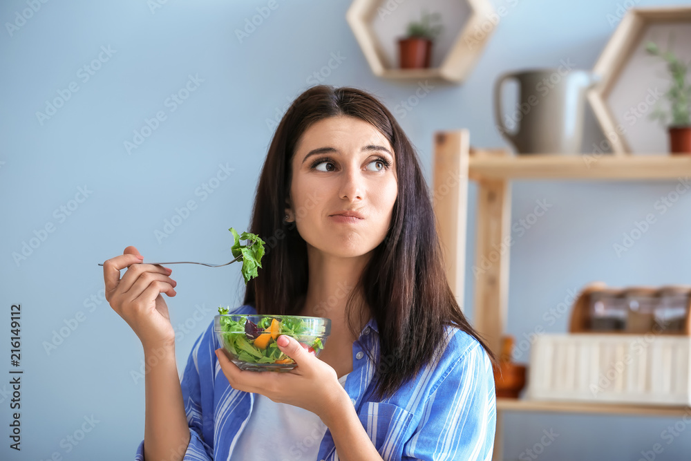 不情愿的女人在室内吃健康沙拉和蔬菜。饮食理念