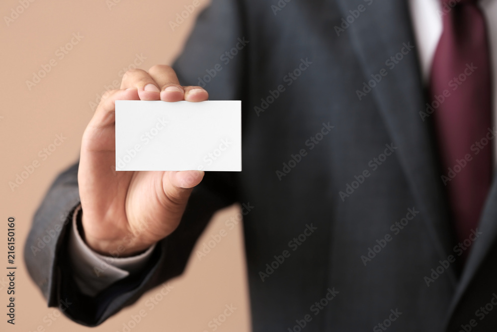 Man with business card on color background, closeup