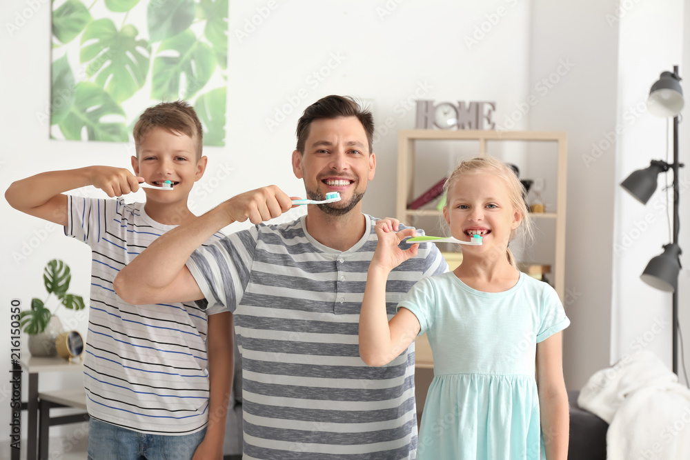 Man and his little children brushing teeth at home