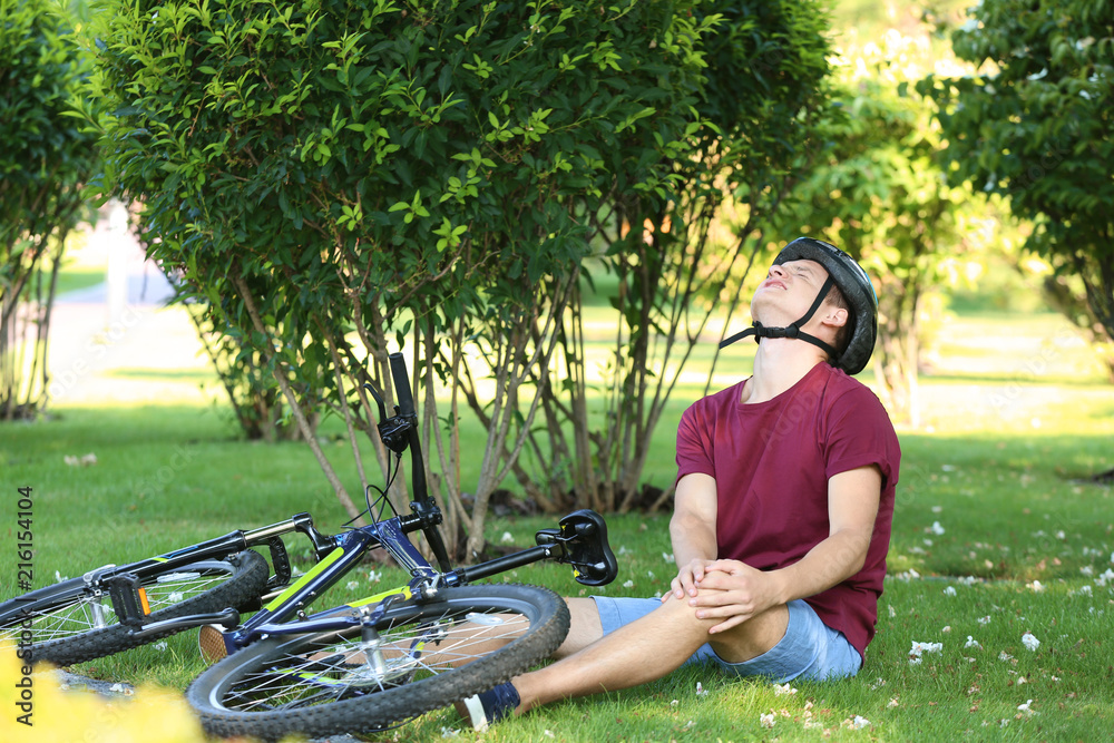 Young man fallen off his bicycle in park