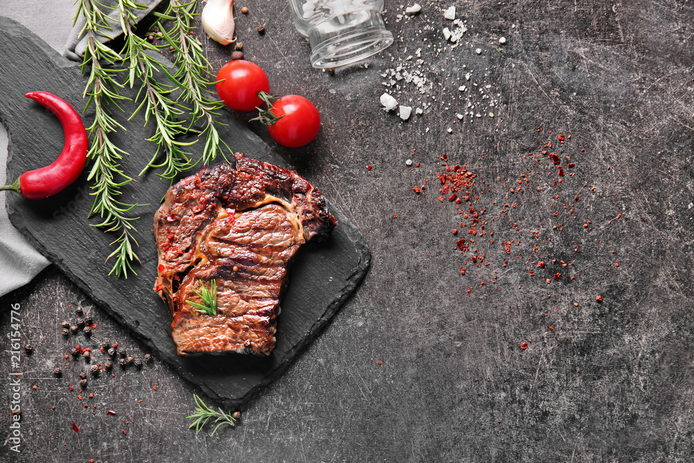 Tasty grilled meat with rosemary and spices on grey background