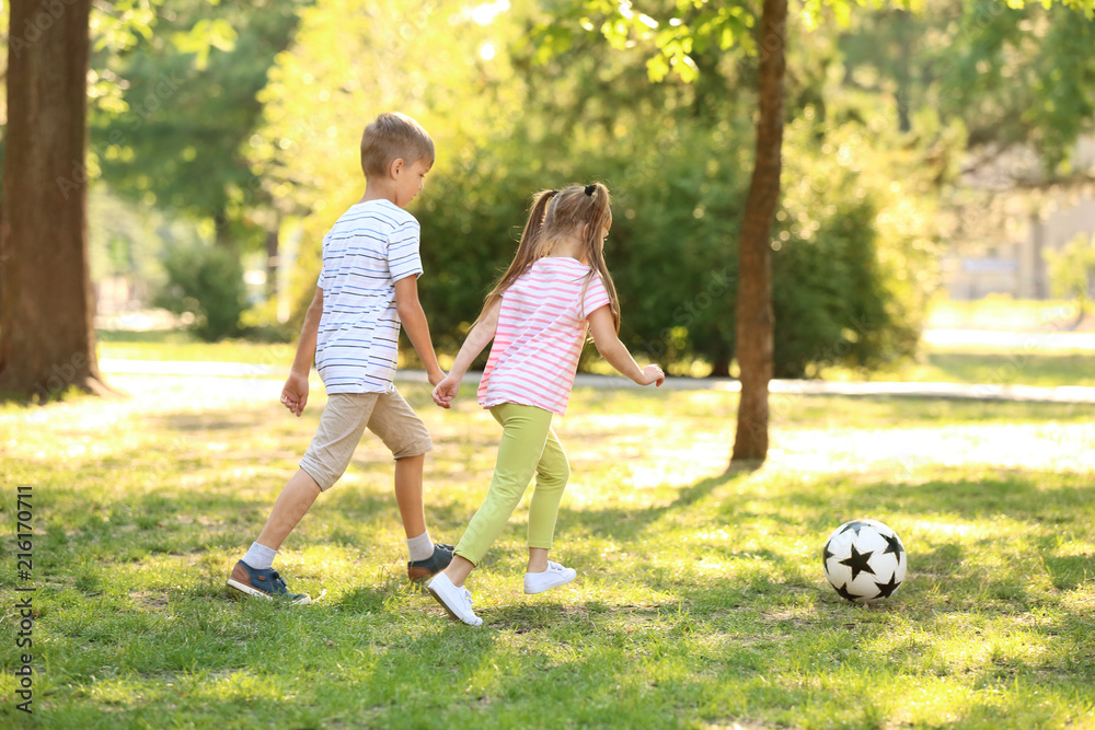 Cute little children playing football outdoors