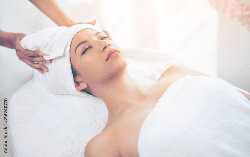 Relaxed young woman lying on spa bed for massage.