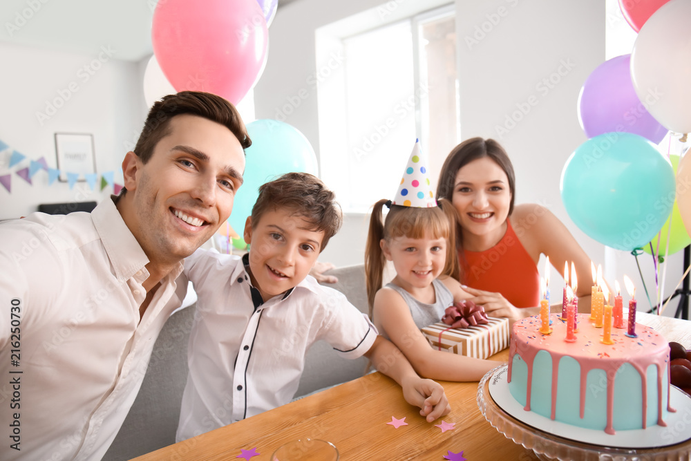 Young man taking selfie with family while celebrating daughters birthday at home