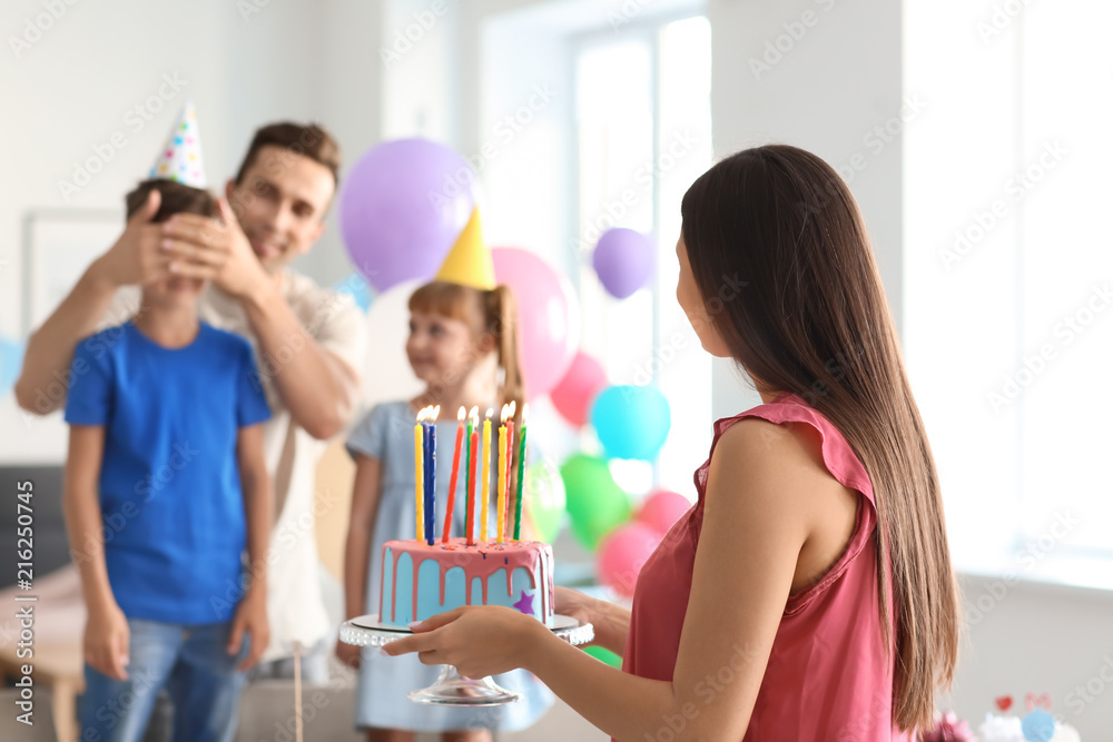 Happy family celebrating birthday with cake at home