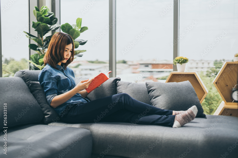 美丽的亚洲女人喜欢在沙发上看书