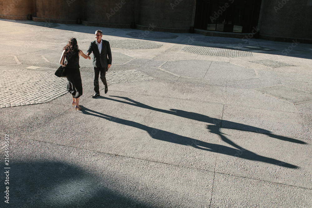 Business colleagues meeting each other on a street while commuti