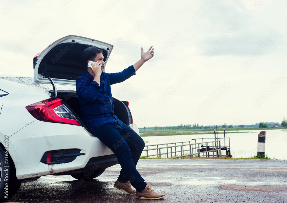 Man sitting by broken down car at countryside