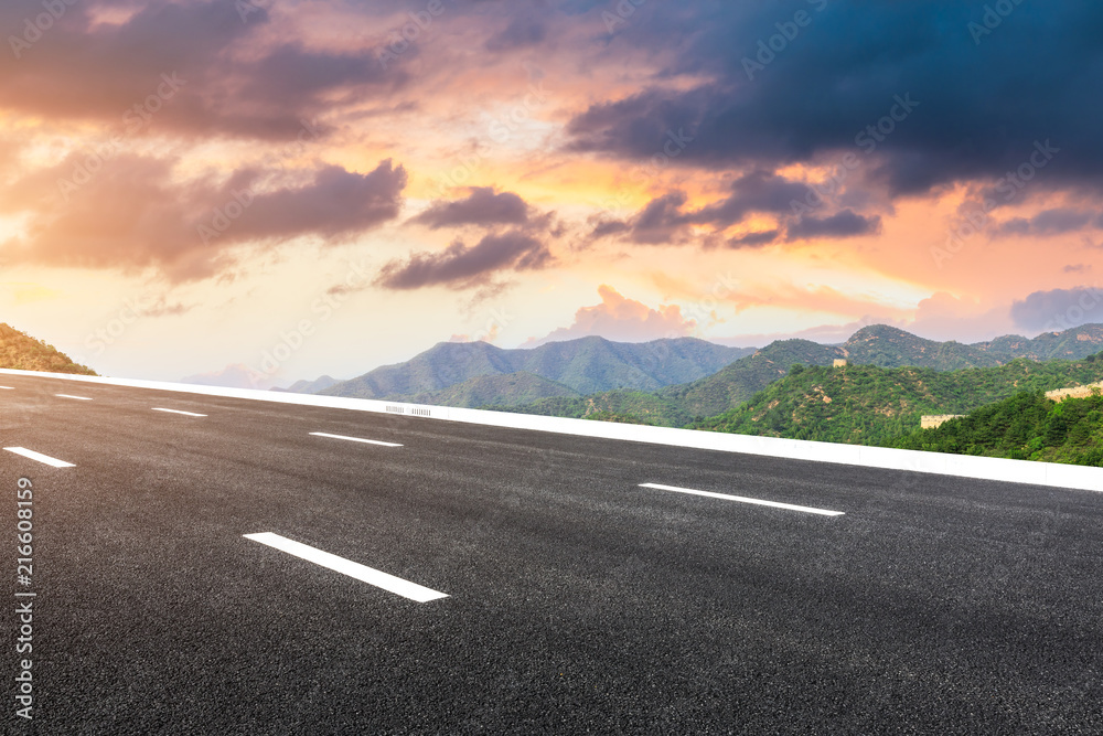 Empty asphalt road and great wall with mountains at sunset