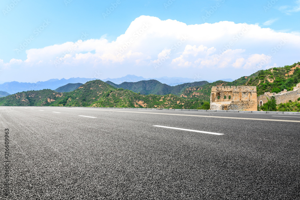 Empty asphalt road and great wall with mountains under the blue sky