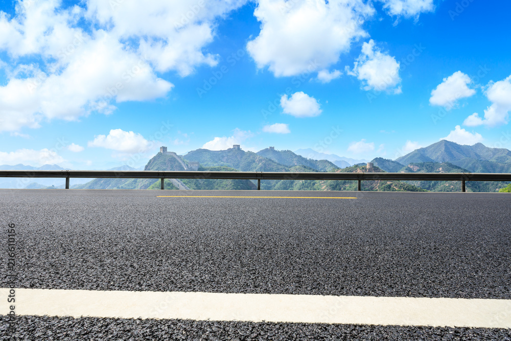 空旷的柏油路和蓝天下群山环绕的长城