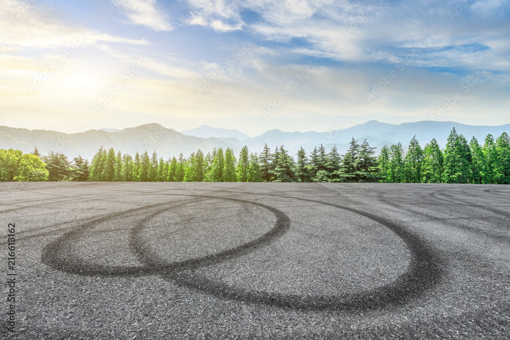 Empty asphalt square and mountain with forest scenery at sunrise