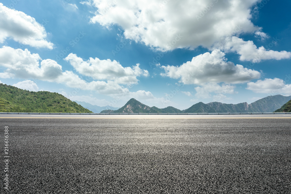 空旷的柏油路和蓝天下的山脉自然风光