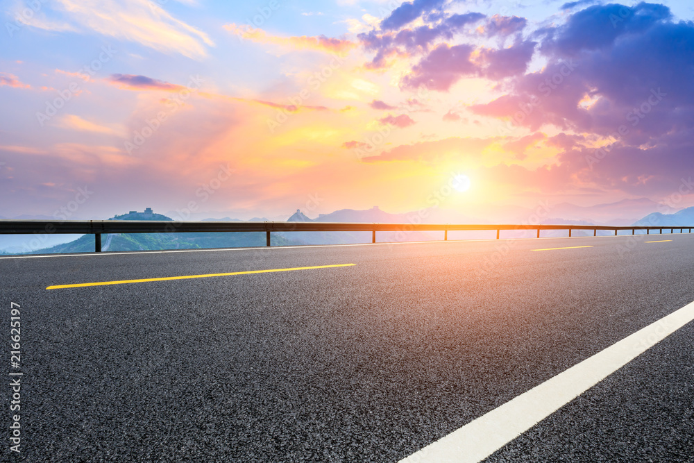 Empty asphalt road and great wall with mountains at sunset