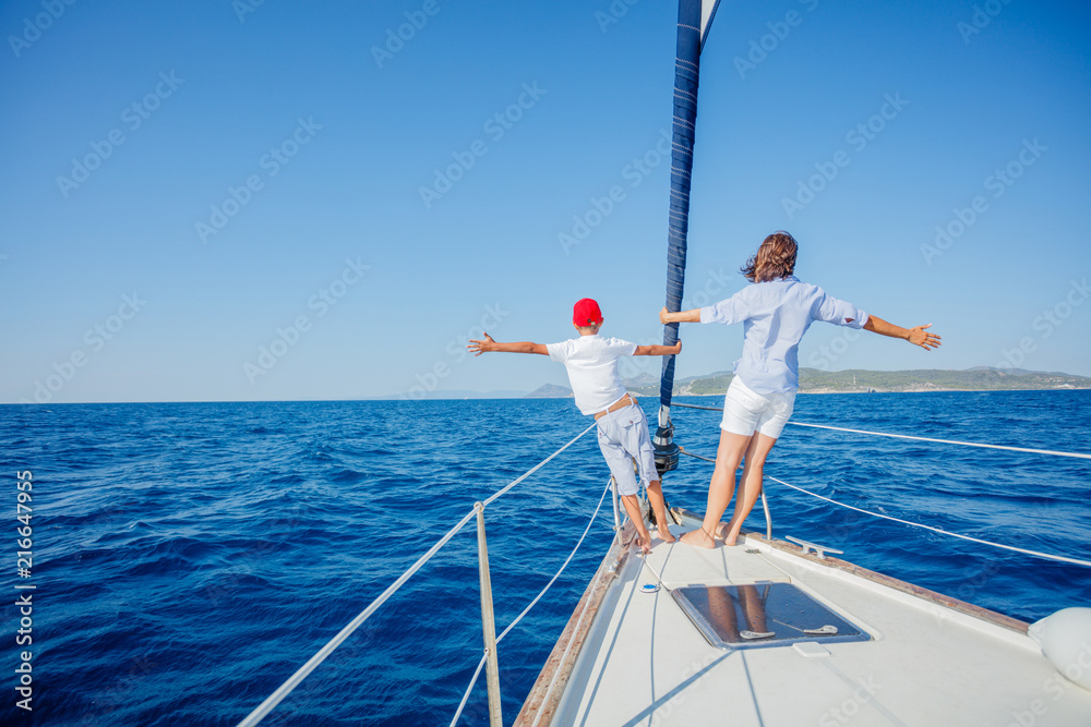 Boy with his mother on board of sailing yacht on summer cruise.