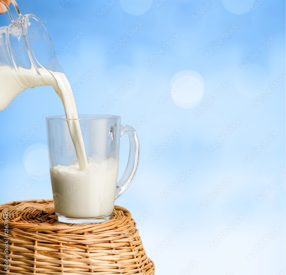 Glass jug of fresh milk on background