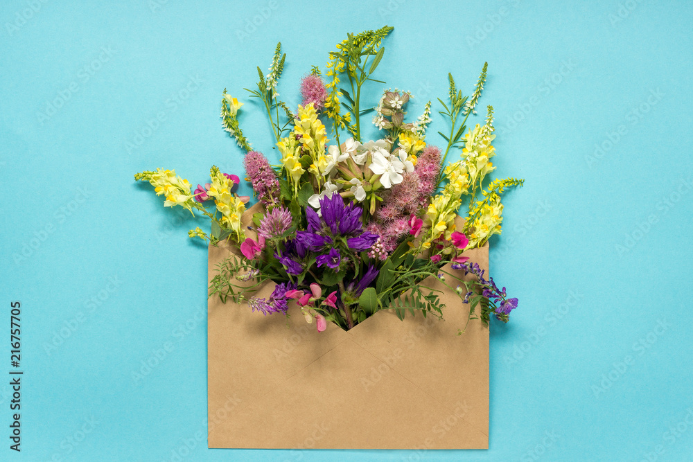 Field colorful rustic vintage flowers in craft envelope on blue