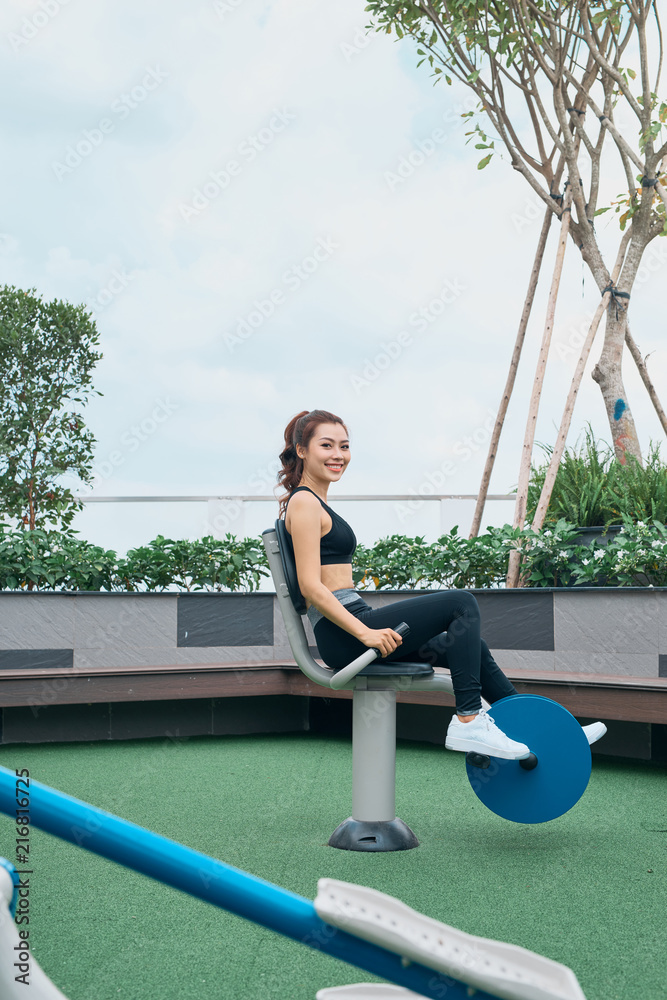 亚洲女性在户外健身房操场设备锻炼