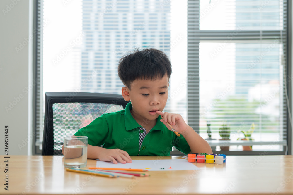 孩子们在学习桌上思考。孩子拿着钢笔和笔记本，脸上有思考的动作。男孩在做ho