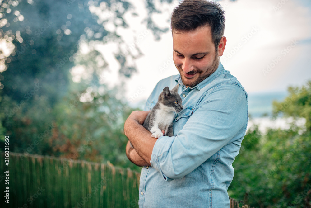 英俊的男人在户外拥抱一只猫。